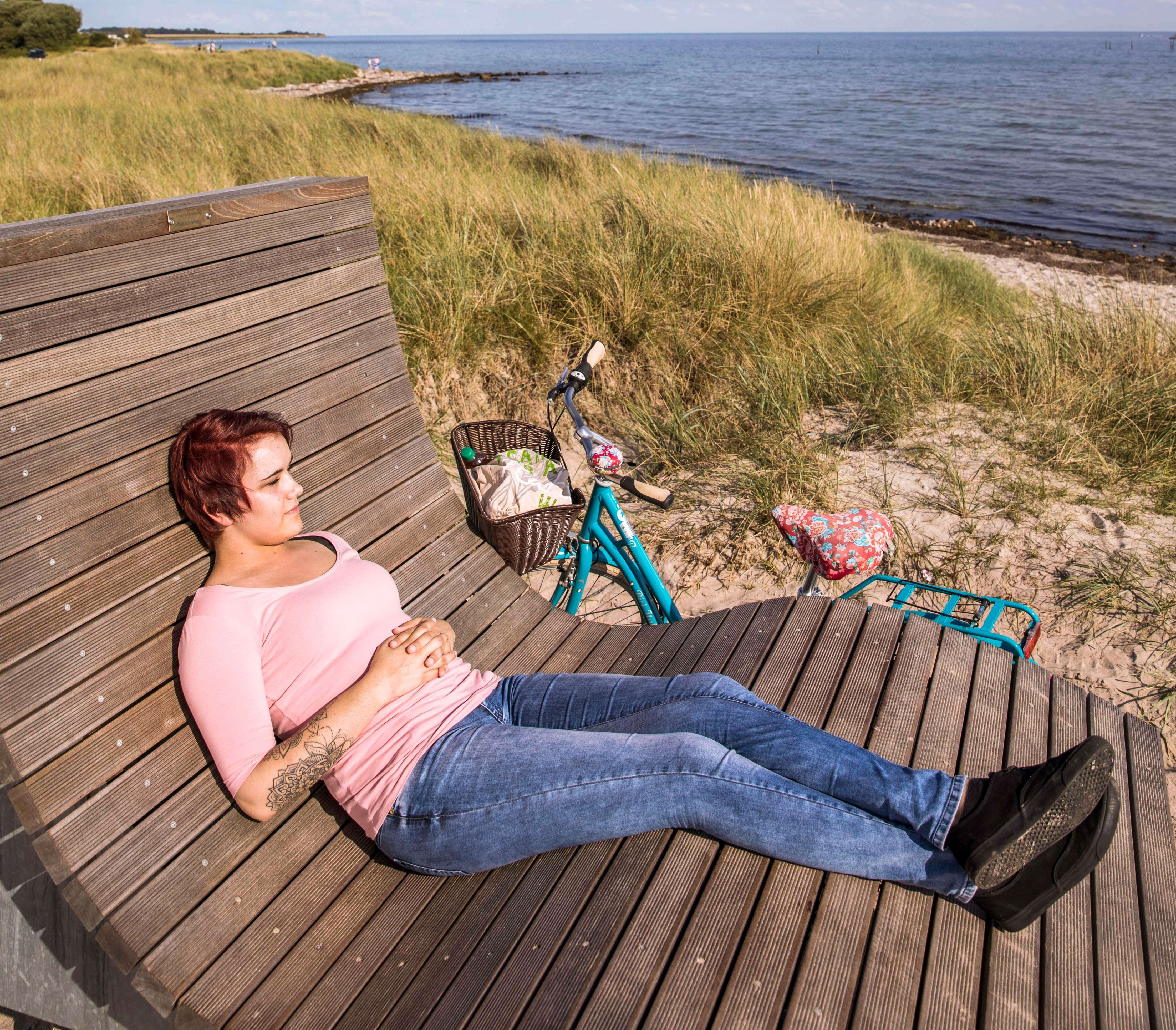 Eine junge Frau macht Pause auf dem Feldsofa während einer Fahrradtour