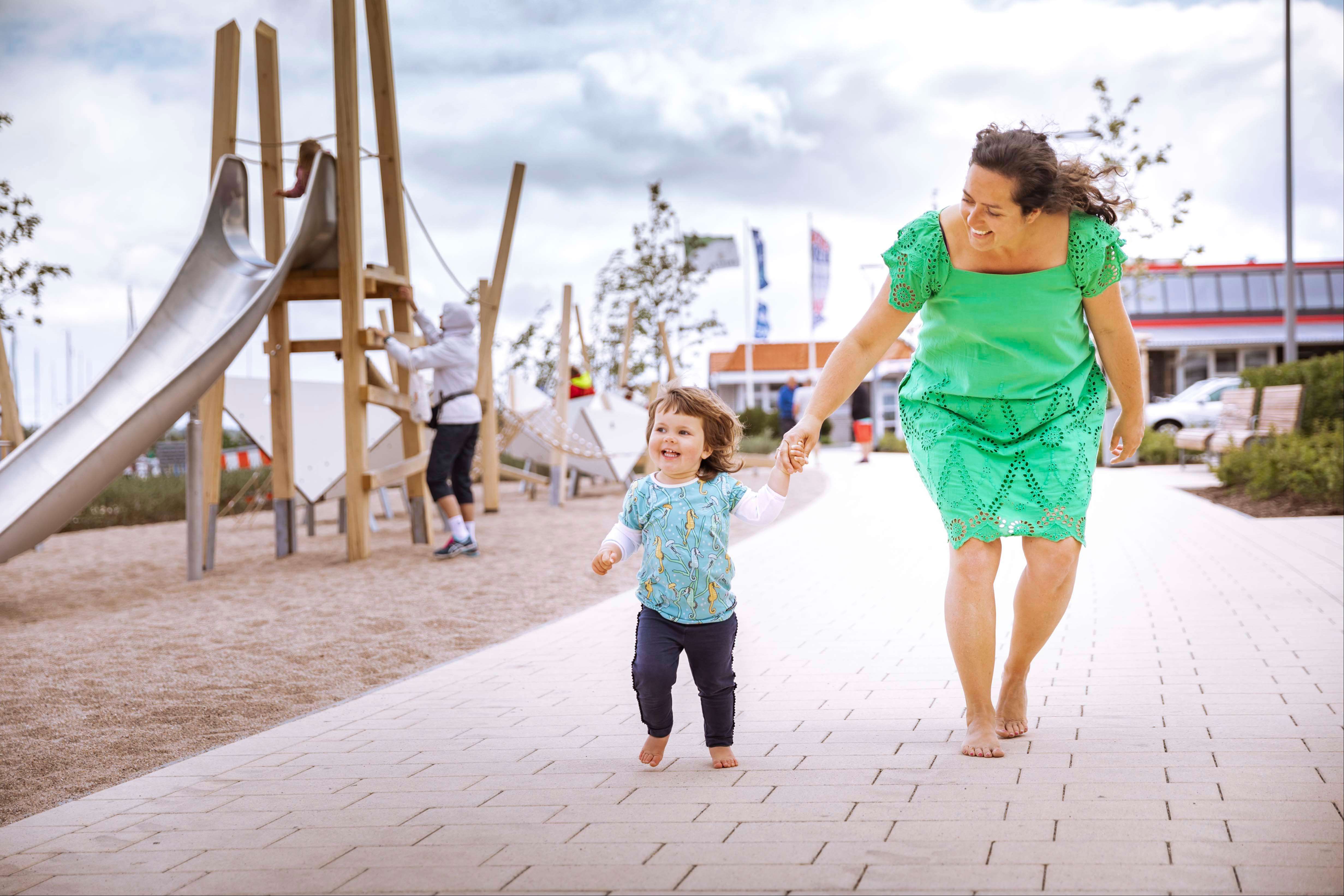 Mutter mit ihrem Kind auf der Yachthafenpromenade in Burgtiefe nahe der Spielplätze 