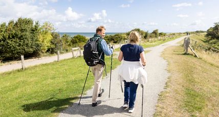 Ein Paar Wandert mit Nordic Walking Stöcken auf dem Deich in Altenteil