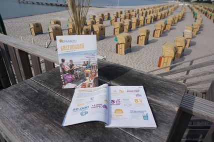 Gastroguide-Broschüre liegt aufgeschlagen auf einem Tisch am Strand