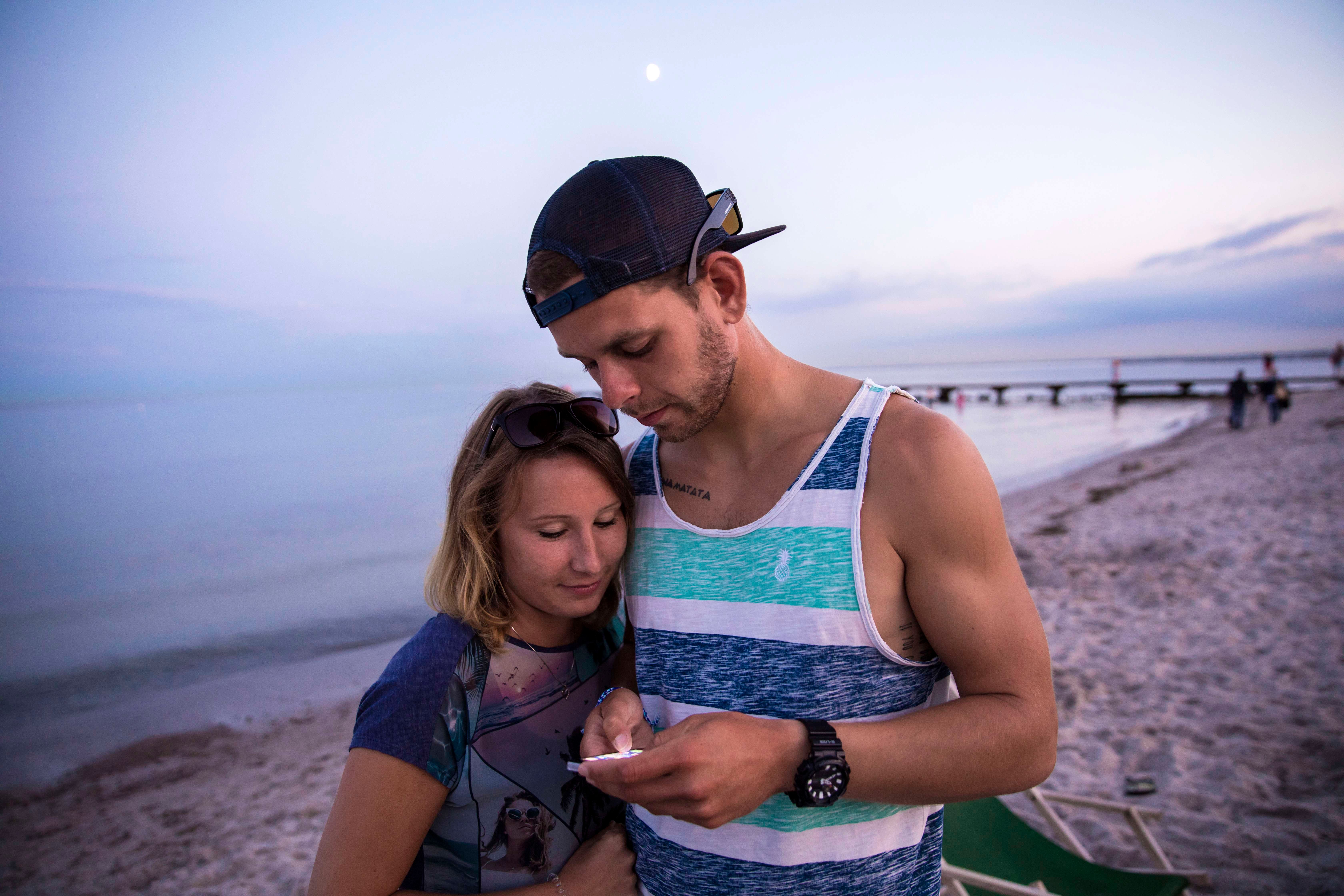  Zwei junge Personen schauen auf ein Handy