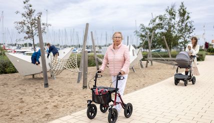 Ältere Dame mit Rollator und Mutter mit Kinderwagen auf der barrierefreien Promenade in Burgtiefe